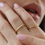 Close-up of a hand wearing the Citrine birthstone gold ring on the pinky finger. 