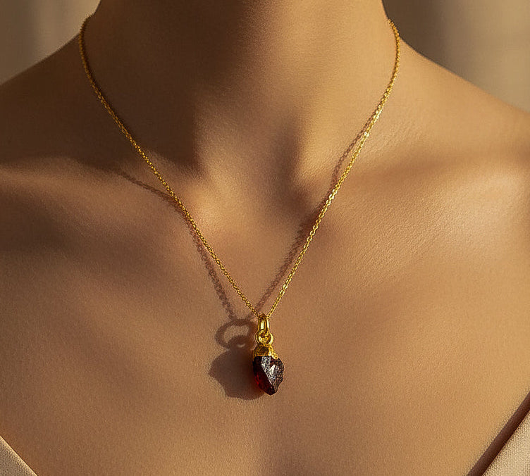 Gold necklace with a red garnet root chakra pendant on a model