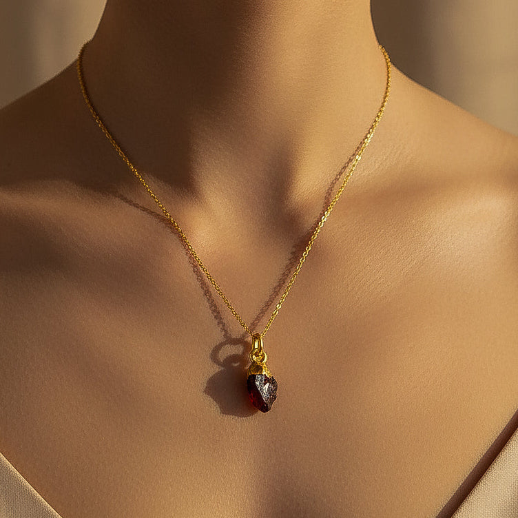 Gold necklace with a red garnet root chakra pendant on a model