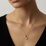 Woman wearing a gold necklace with a raw citrine chakra pendant against a neutral background