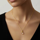 Woman wearing a gold necklace with a raw citrine chakra pendant against a neutral background