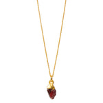 A raw crystal garnet pendant attached to a gold-filled chain against a white background